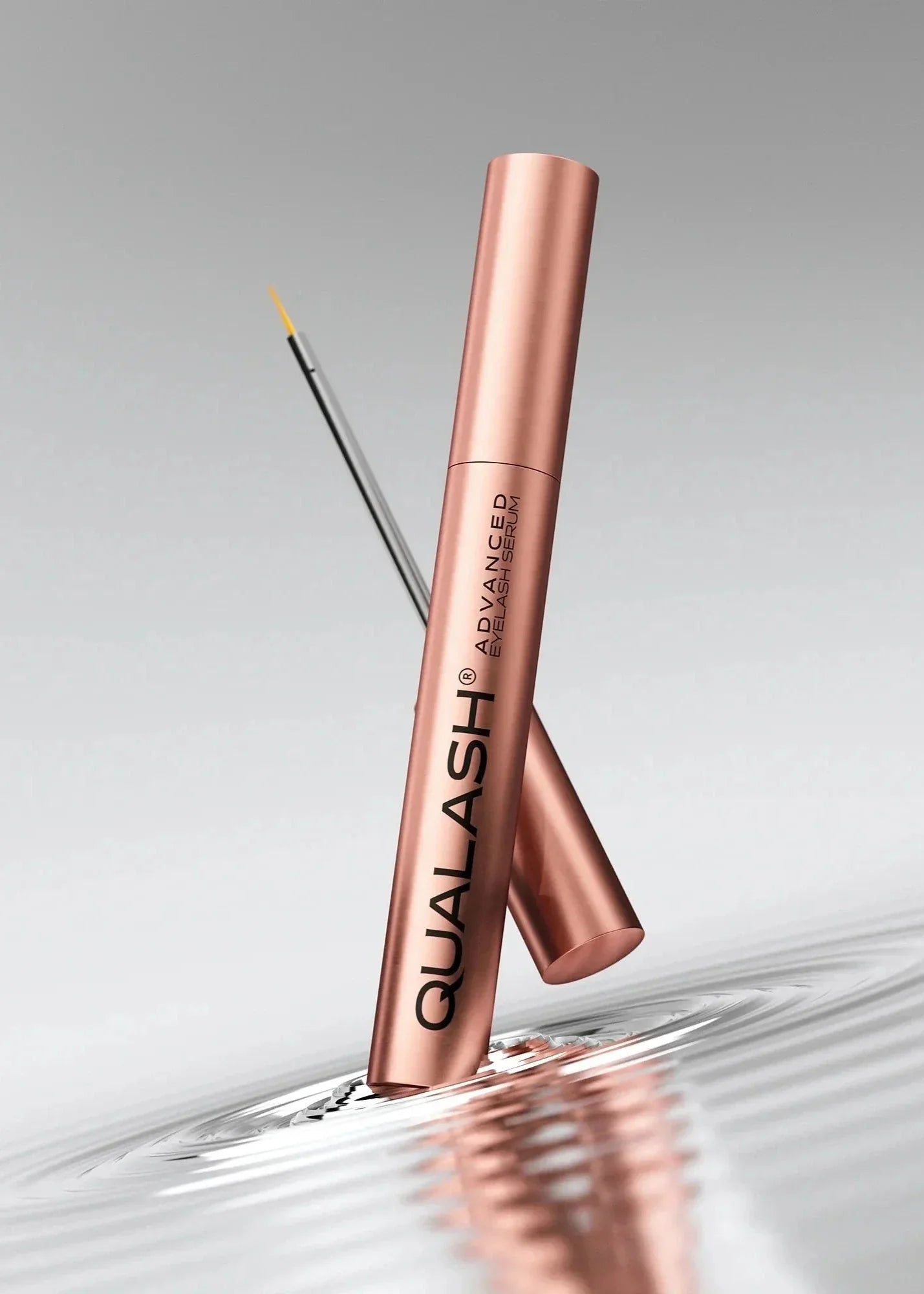 QUALASH Advanced Eyelash Serum standing in a ripple of water, silver background