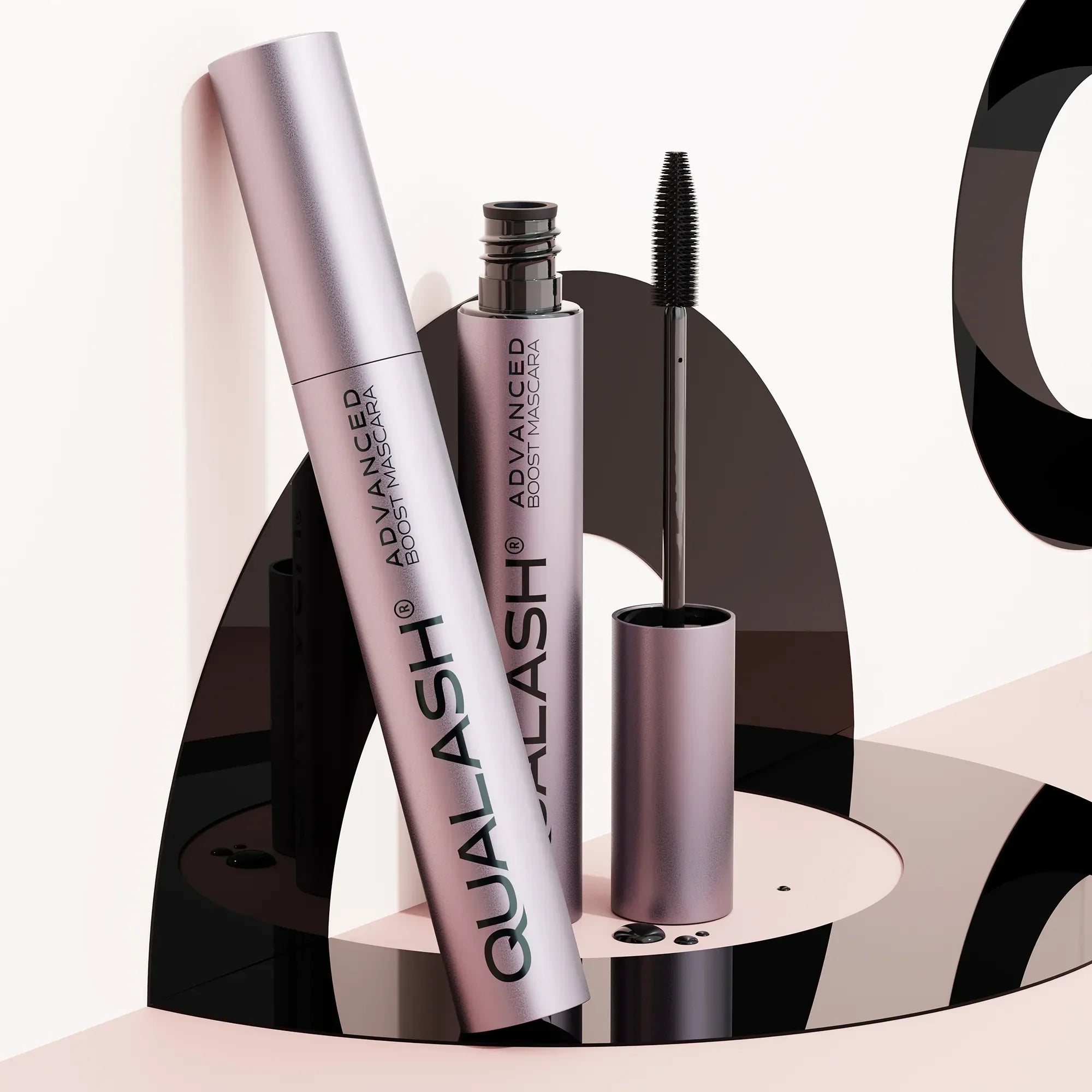 QUALASH Advanced Boost Mascara set displayed on modern artistic black and pink setup